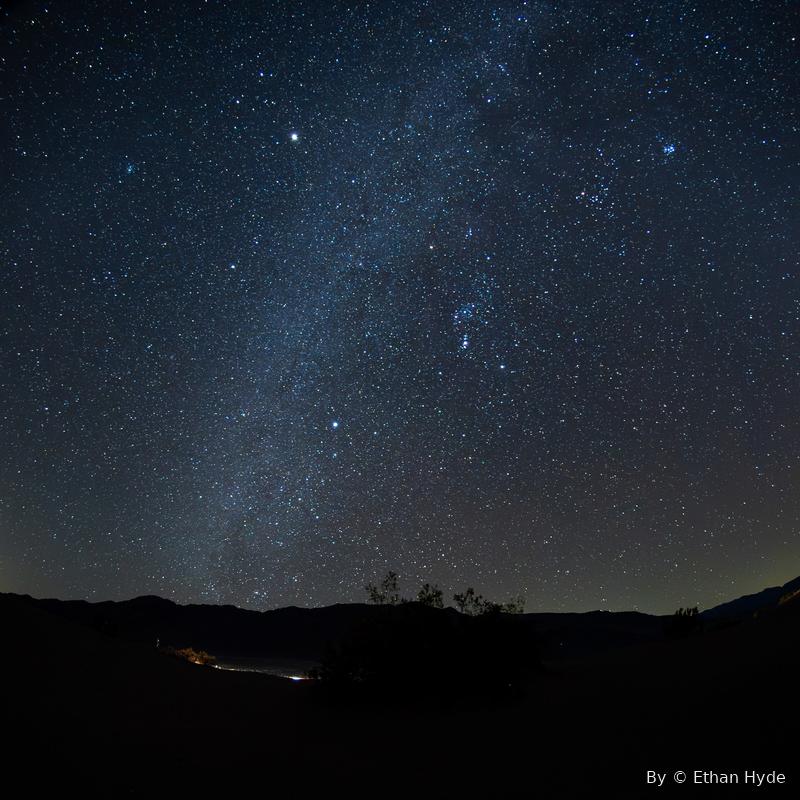 The dense band of the Milky Way rising over a dark mountain horizon.