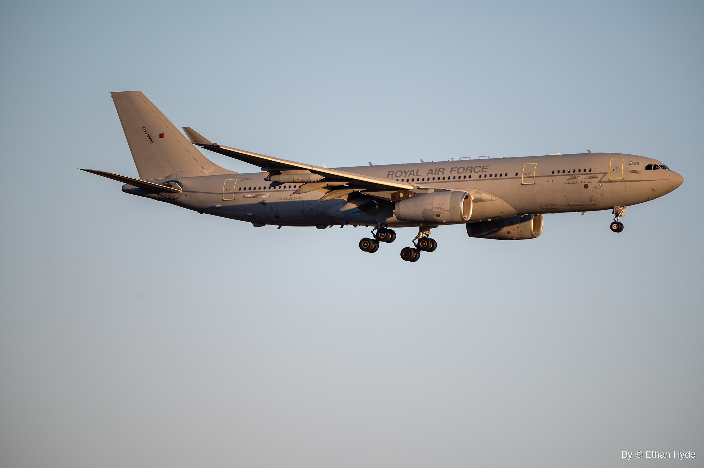A gray Royal Air Force A330 Voyager tanker descends toward landing with its gear down against a pale blue-gray sky.