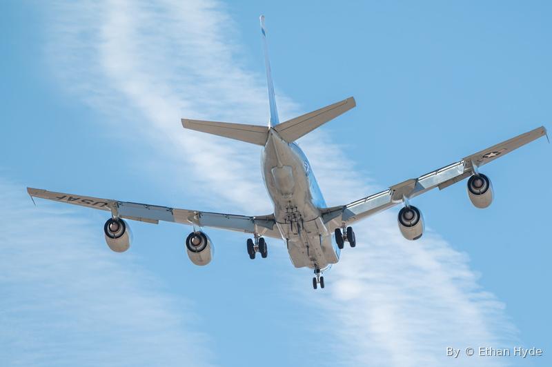 A large four-engine military jet on final approach, gear down, seen head-on.