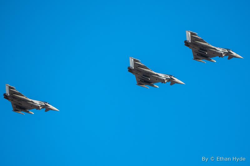 Four fighter jets flying in tight formation across a clear blue sky.