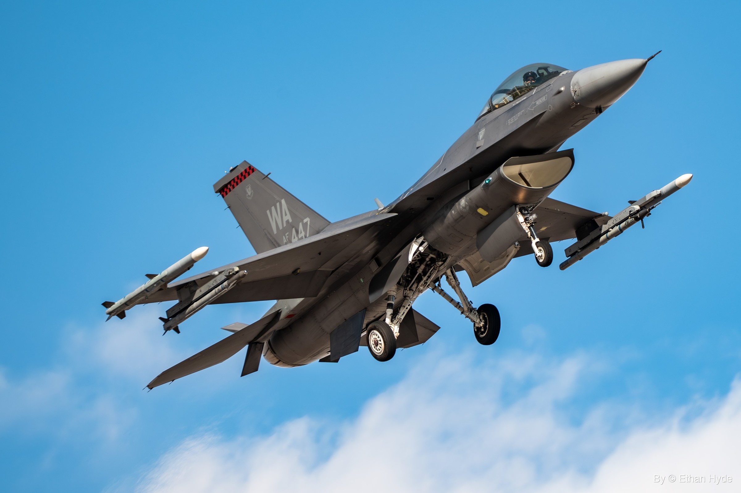 An F-16 fighter jet banking through a clear blue sky.