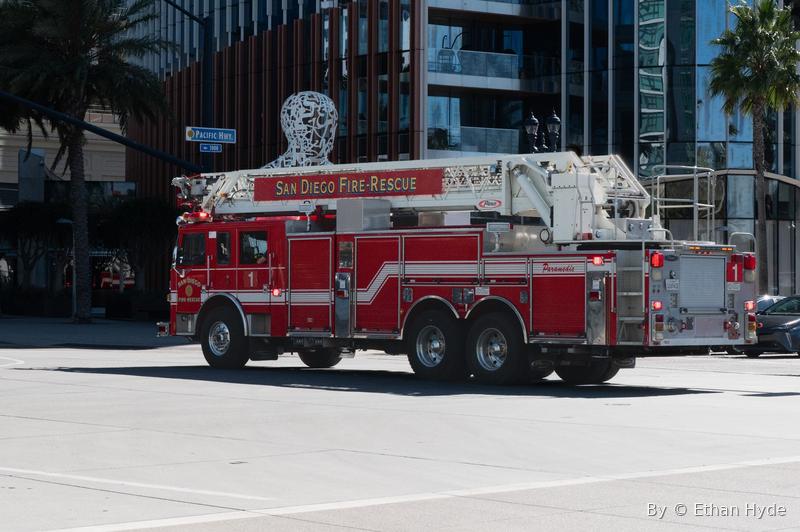 A red fire-department ladder truck parked on a city street.