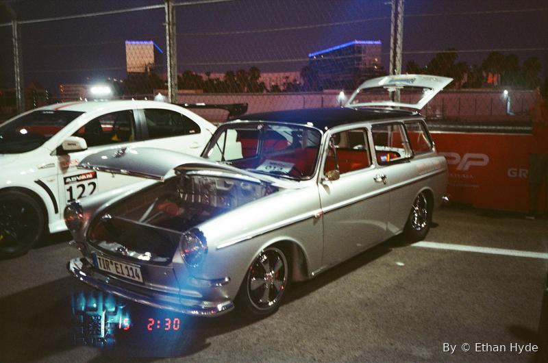 A lowered silver Volkswagen Type 3 squareback at a night car meet, glow on the pavement.