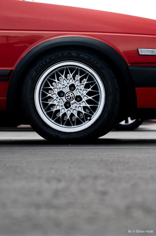 Close-up of a polished wire-spoke wheel on a red classic car.