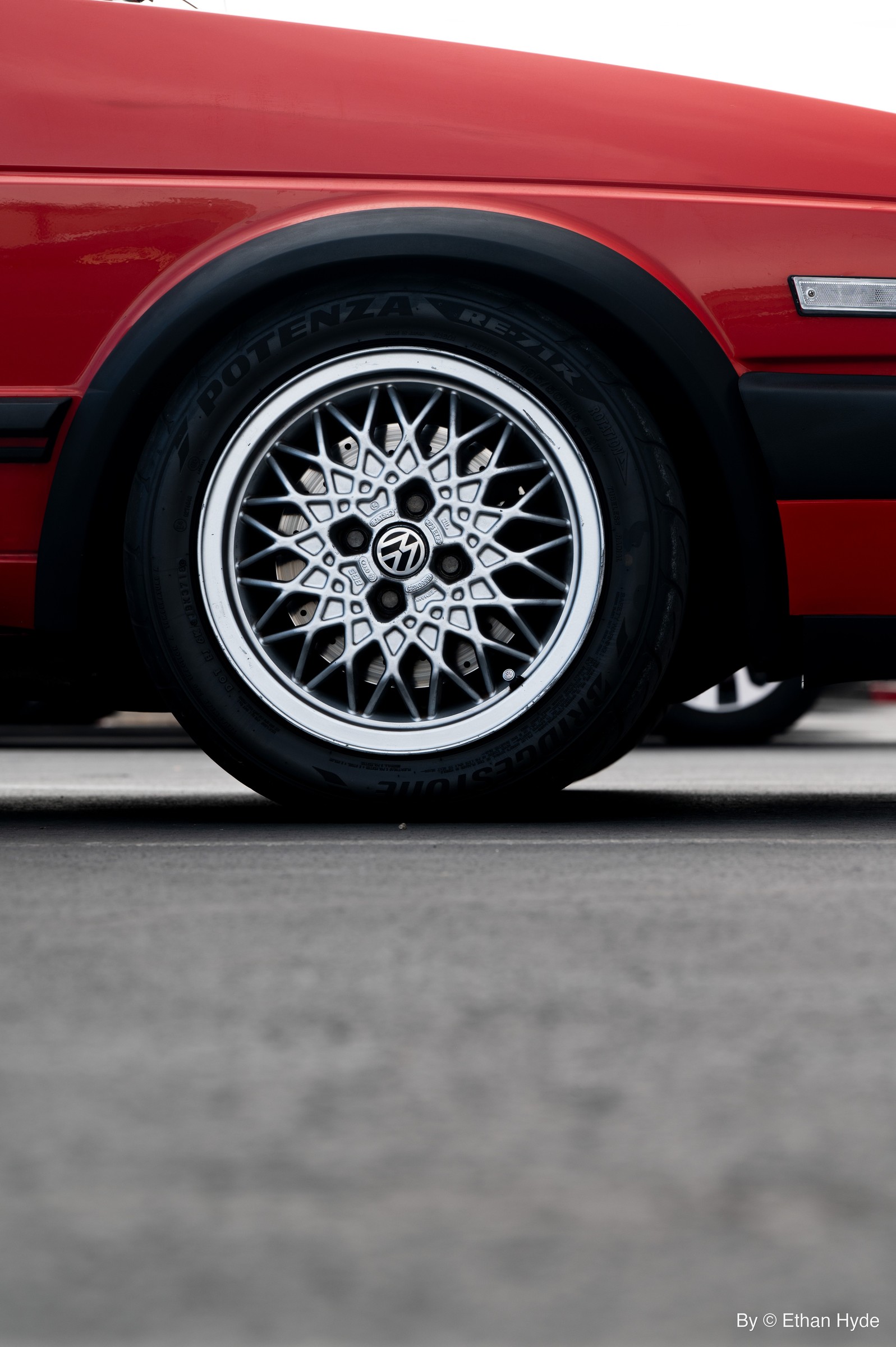 Close-up of a polished wire-spoke wheel on a red classic car.