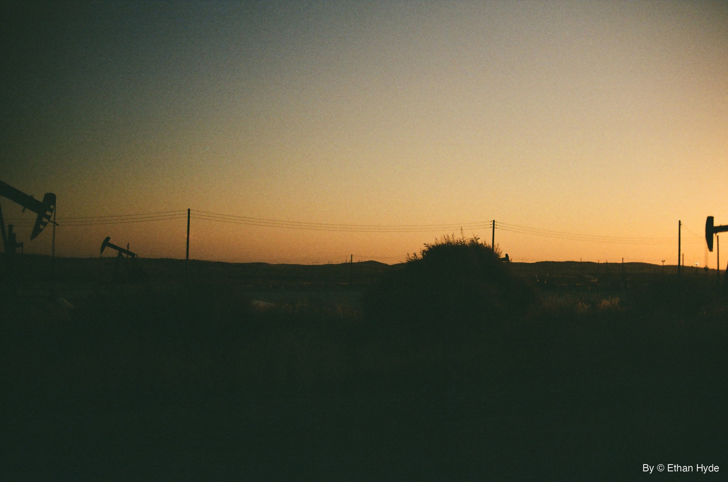 Pumpjacks silhouetted against an orange dawn sky over the oil fields near McKittrick, California, shot on film.