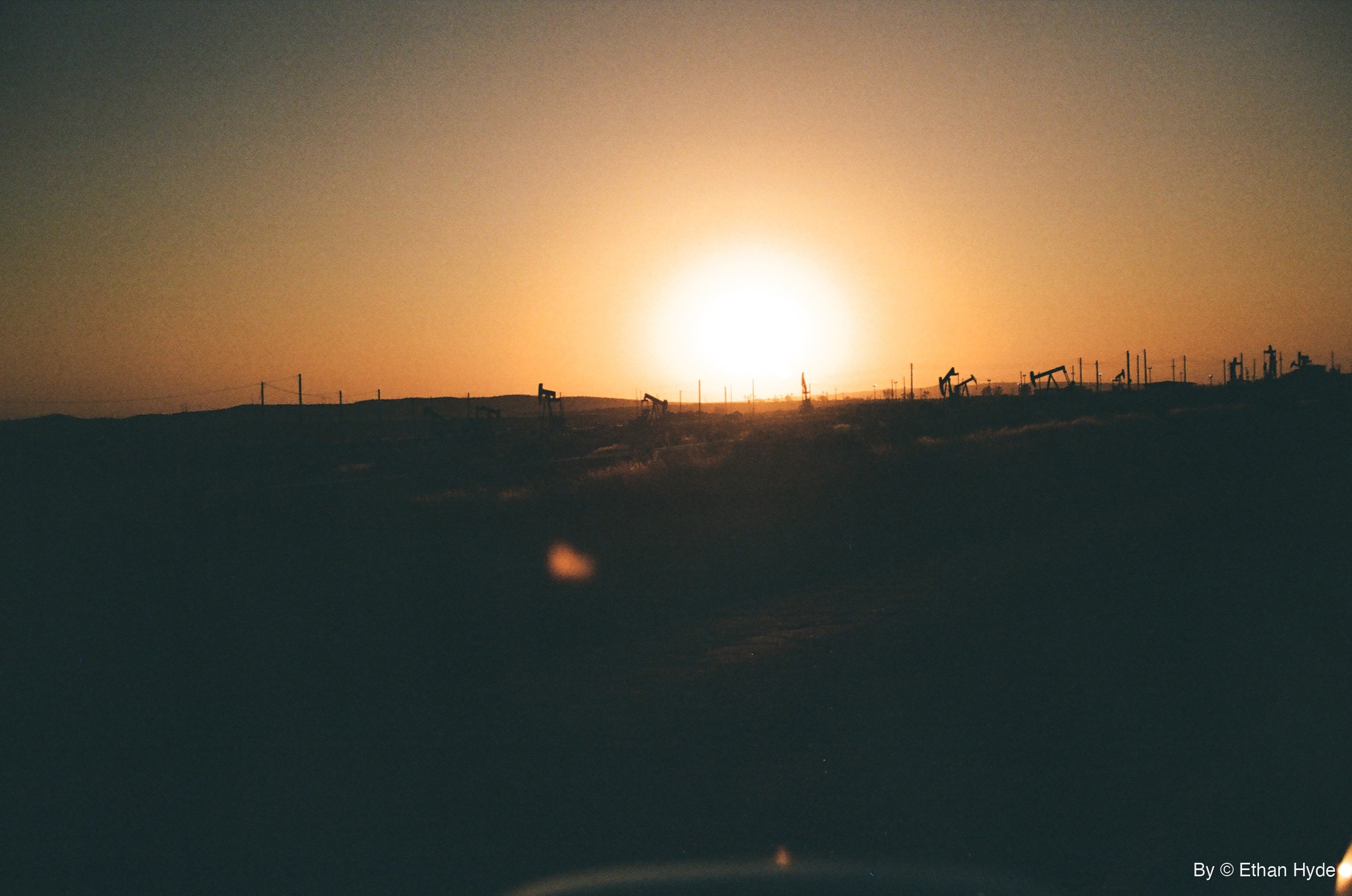 The sun breaks the horizon behind a line of pumpjacks near McKittrick, California, shot on film.