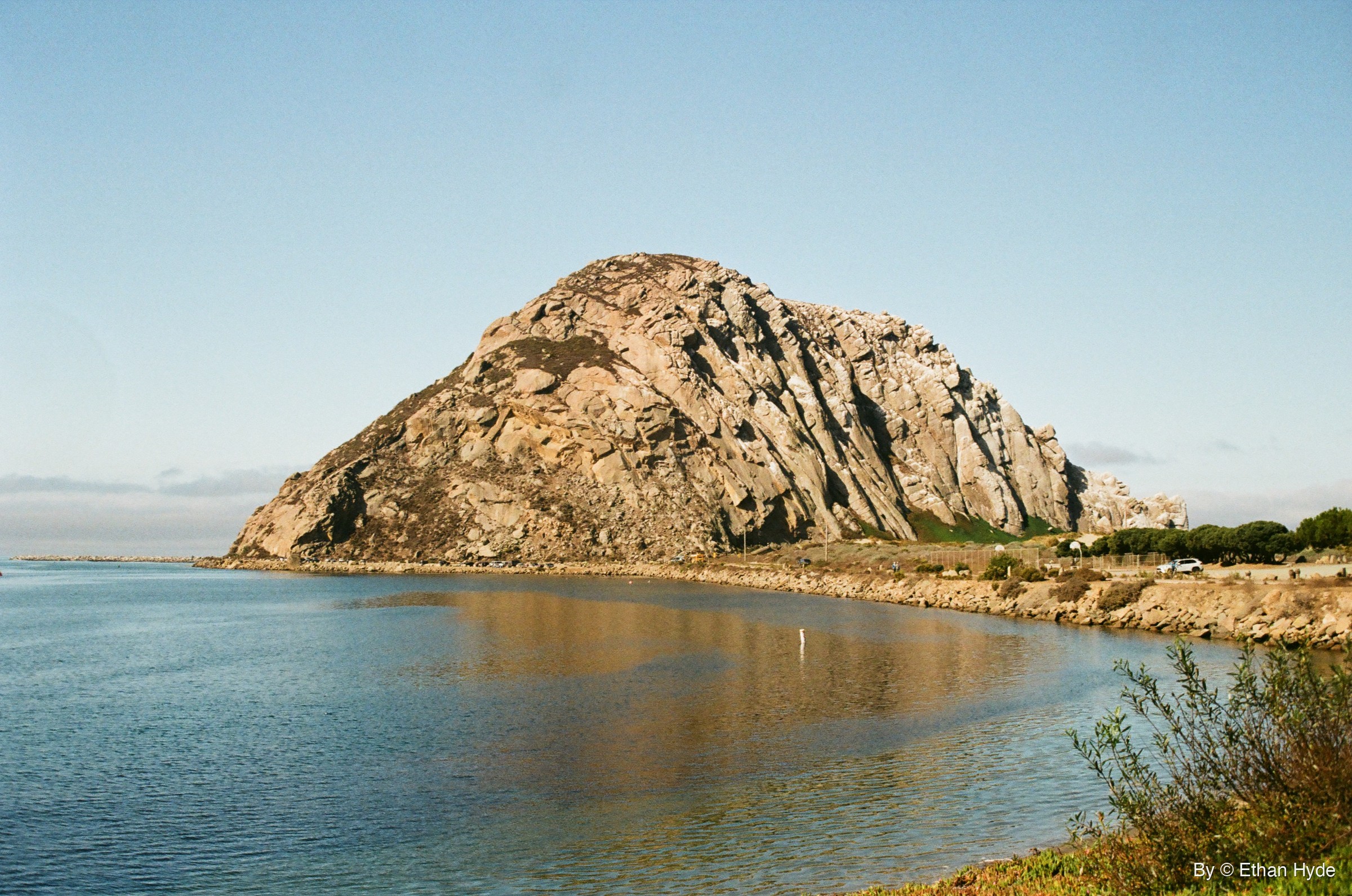 Morro Rock rising above calm blue water on the Central California coast, shot on film.