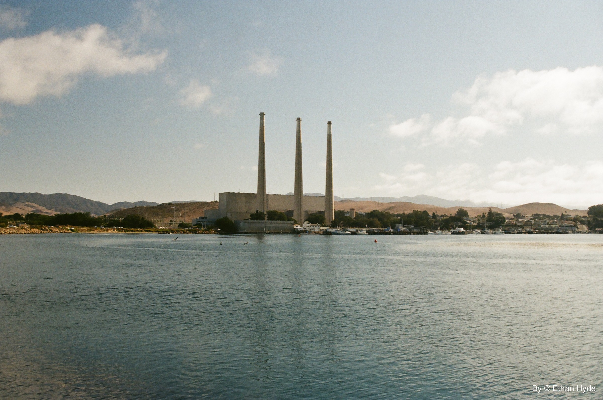 The Morro Bay power plant's three smokestacks reflected across the water, shot on film.