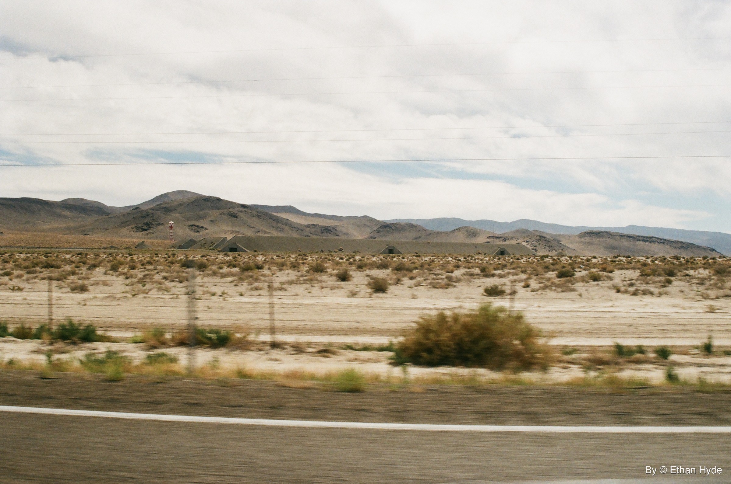Rows of earth-covered ammunition bunkers below desert mountains near Hawthorne, Nevada, seen from the highway on film.