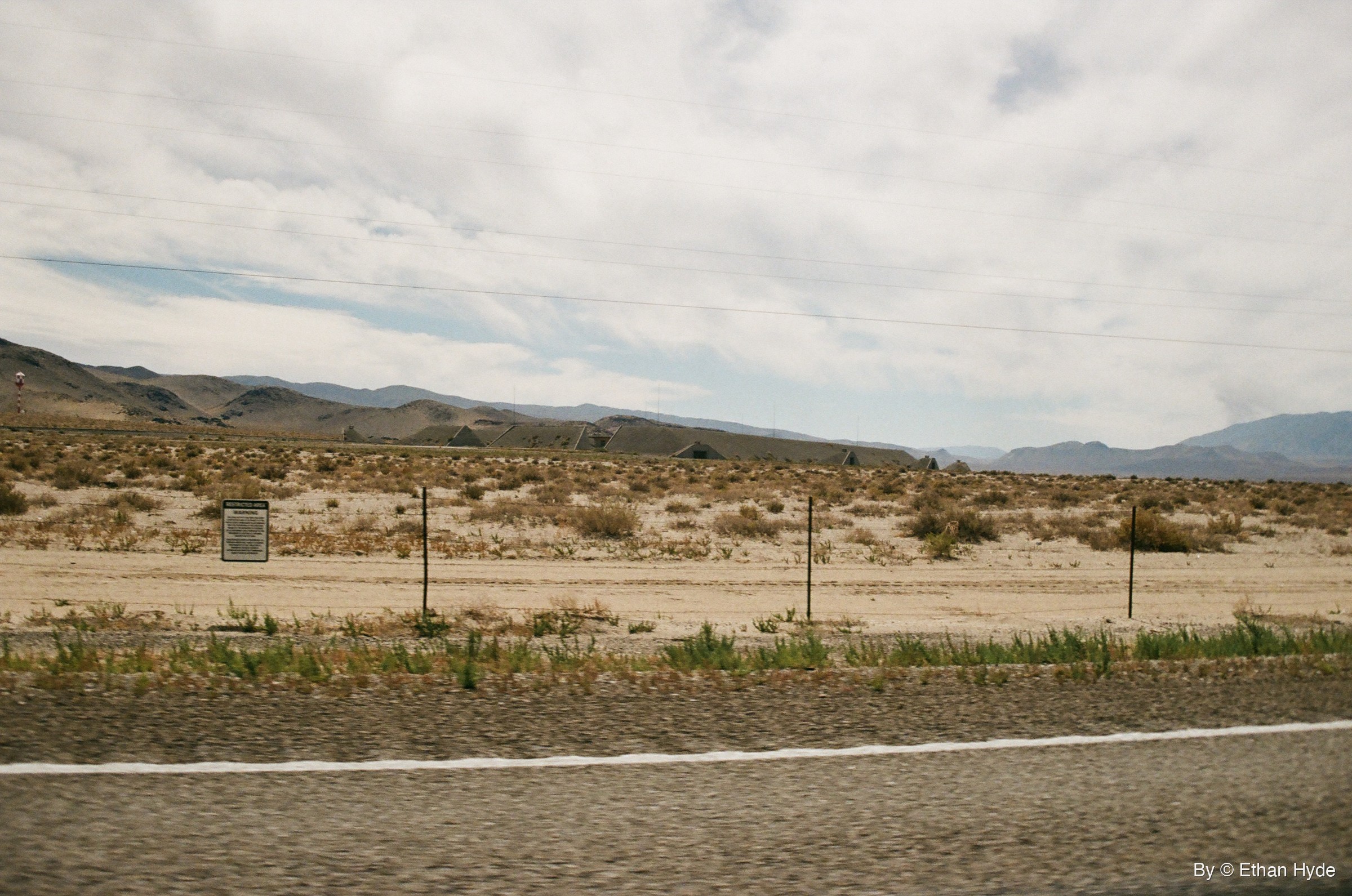 A line of ammunition bunkers and fence posts beneath a cloudy sky near Hawthorne, Nevada, shot on film.