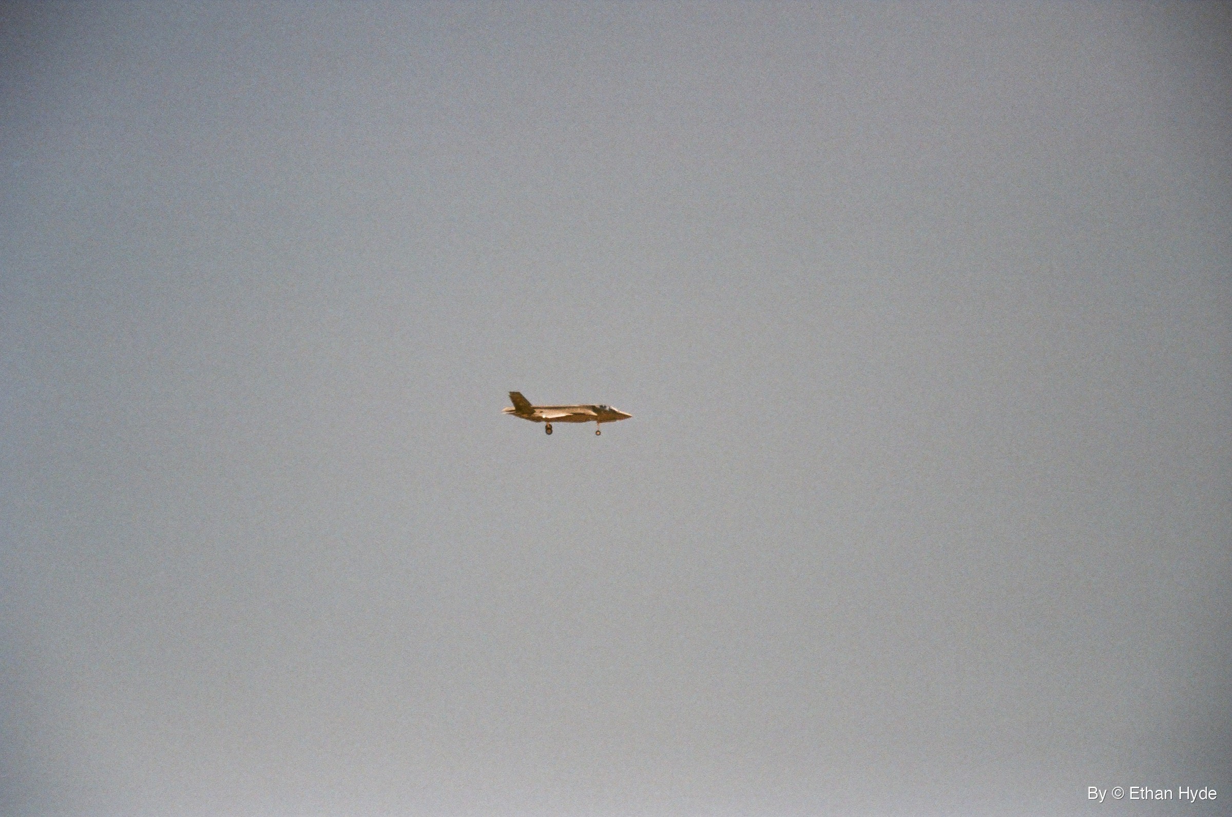An F-35 crossing a pale grey sky, shot on film.