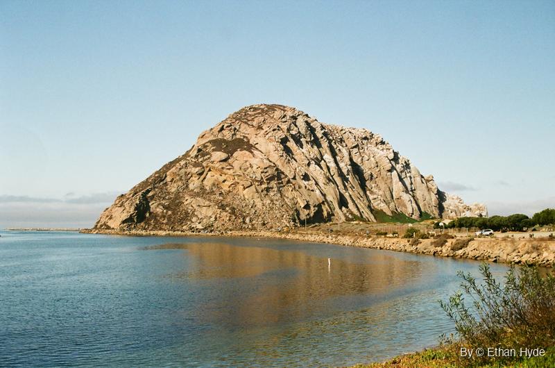 Morro Rock rising above calm blue water on the Central California coast, shot on film.