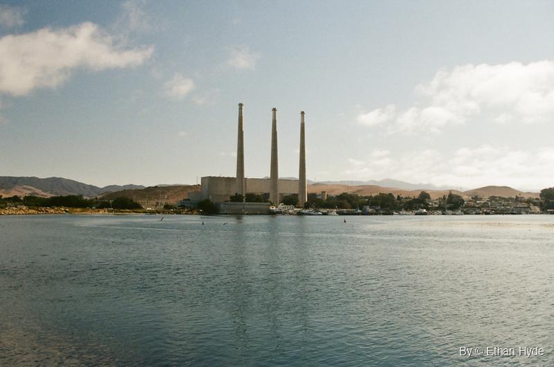 The Morro Bay power plant's three smokestacks reflected across the water, shot on film.