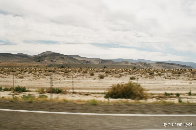 Rows of earth-covered ammunition bunkers below desert mountains near Hawthorne, Nevada, seen from the highway on film.