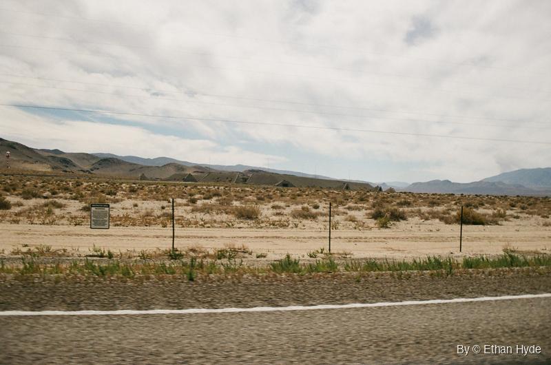 A line of ammunition bunkers and fence posts beneath a cloudy sky near Hawthorne, Nevada, shot on film.