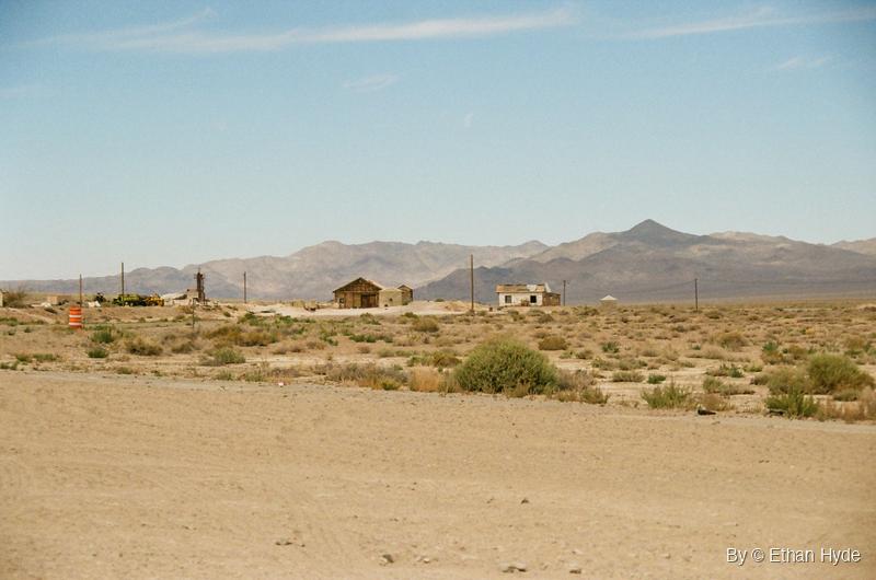 Small buildings scattered across open desert beneath bare mountains in Luning, Nevada, shot on film.