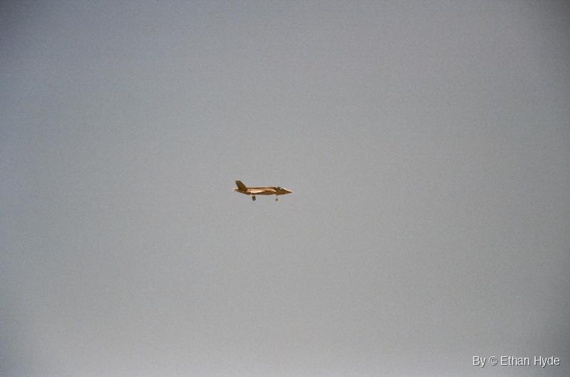 An F-35 crossing a pale grey sky, shot on film.