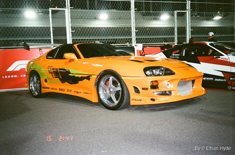 An orange Toyota Supra under garage lights, shot on film.