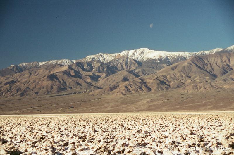 A snow-capped mountain range above a pale desert basin, shot on film.