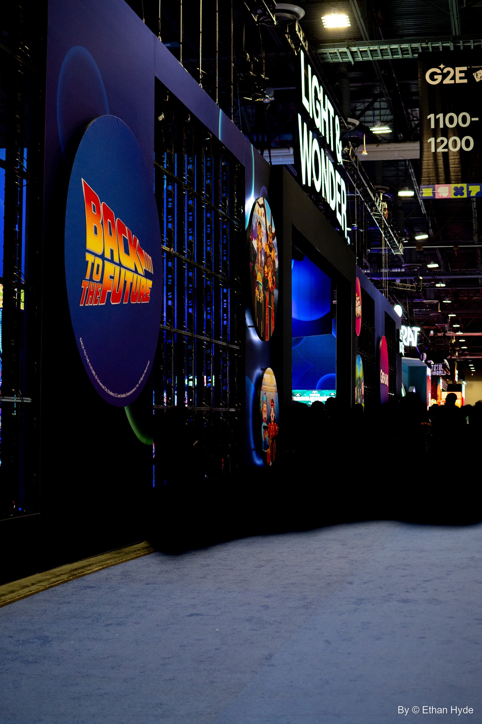 A dark exhibitor booth at G2E with a glowing Back to the Future logo on a circular screen.