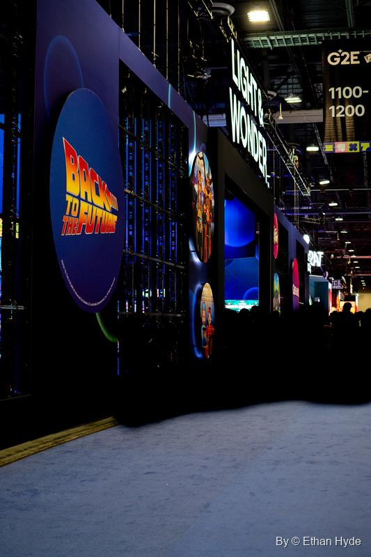 A dark exhibitor booth at G2E with a glowing Back to the Future logo on a circular screen.