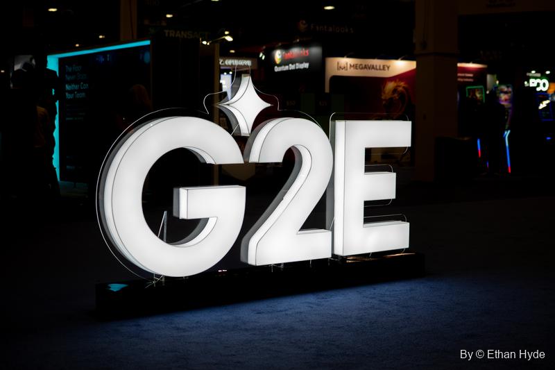 Large illuminated white G2E letters stand on the dark show floor in front of lit exhibitor booths.
