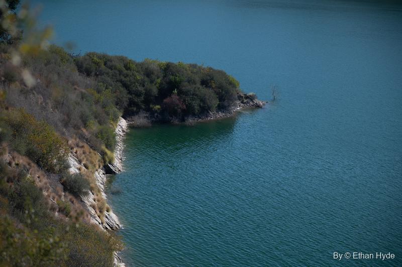 A brushy rock point juts into deep teal water on Lake Casitas.