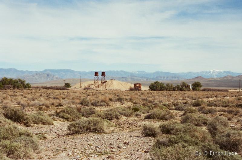 Open desert scrub with a water tank and distant mountains under a wide sky.