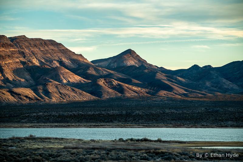 Desert mountains above a still lake, warm light across the water.