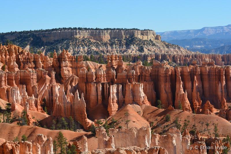 Eroded orange rock spires and hoodoos rising in tiers under a blue sky.