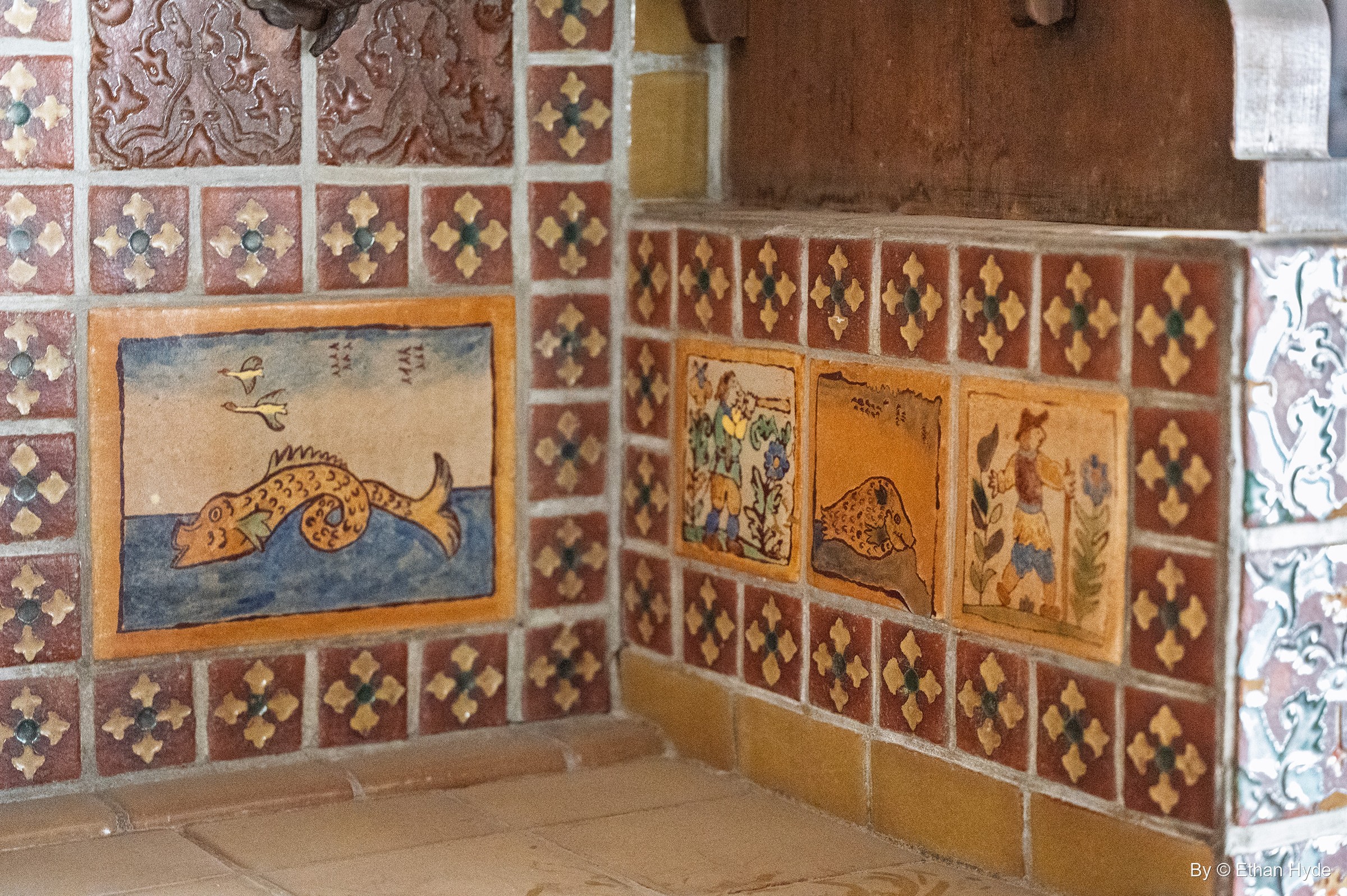 A large hand-painted fish tile panel and figure tiles set among red and gold patterned tile in a corner of the kitchen at Scotty's Castle.