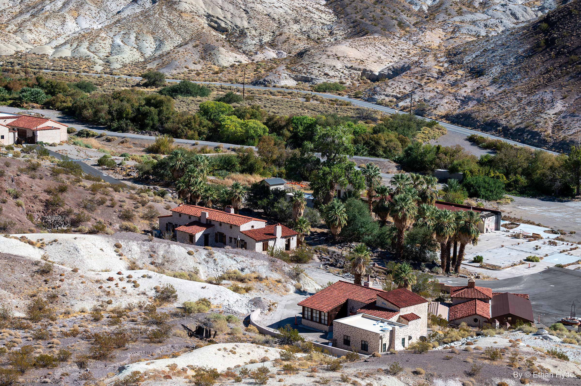 Looking down from the hills over the palms and red-roofed outbuildings of the Scotty's Castle oasis, the canyon road winding past.