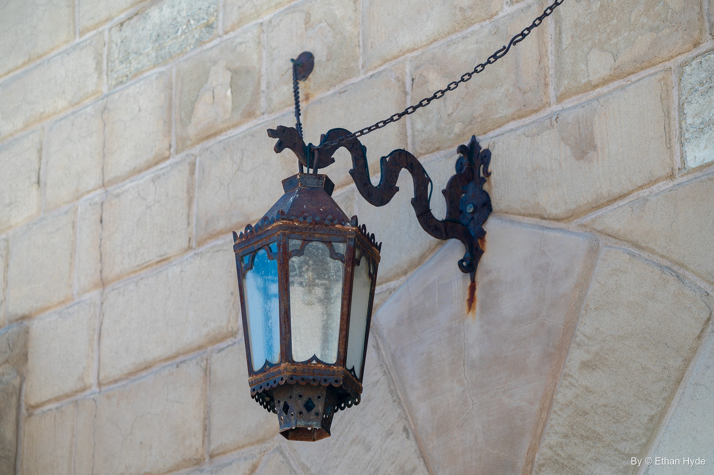 A wrought-iron lantern on a scrolled bracket against the stone-block wall of Scotty's Castle.