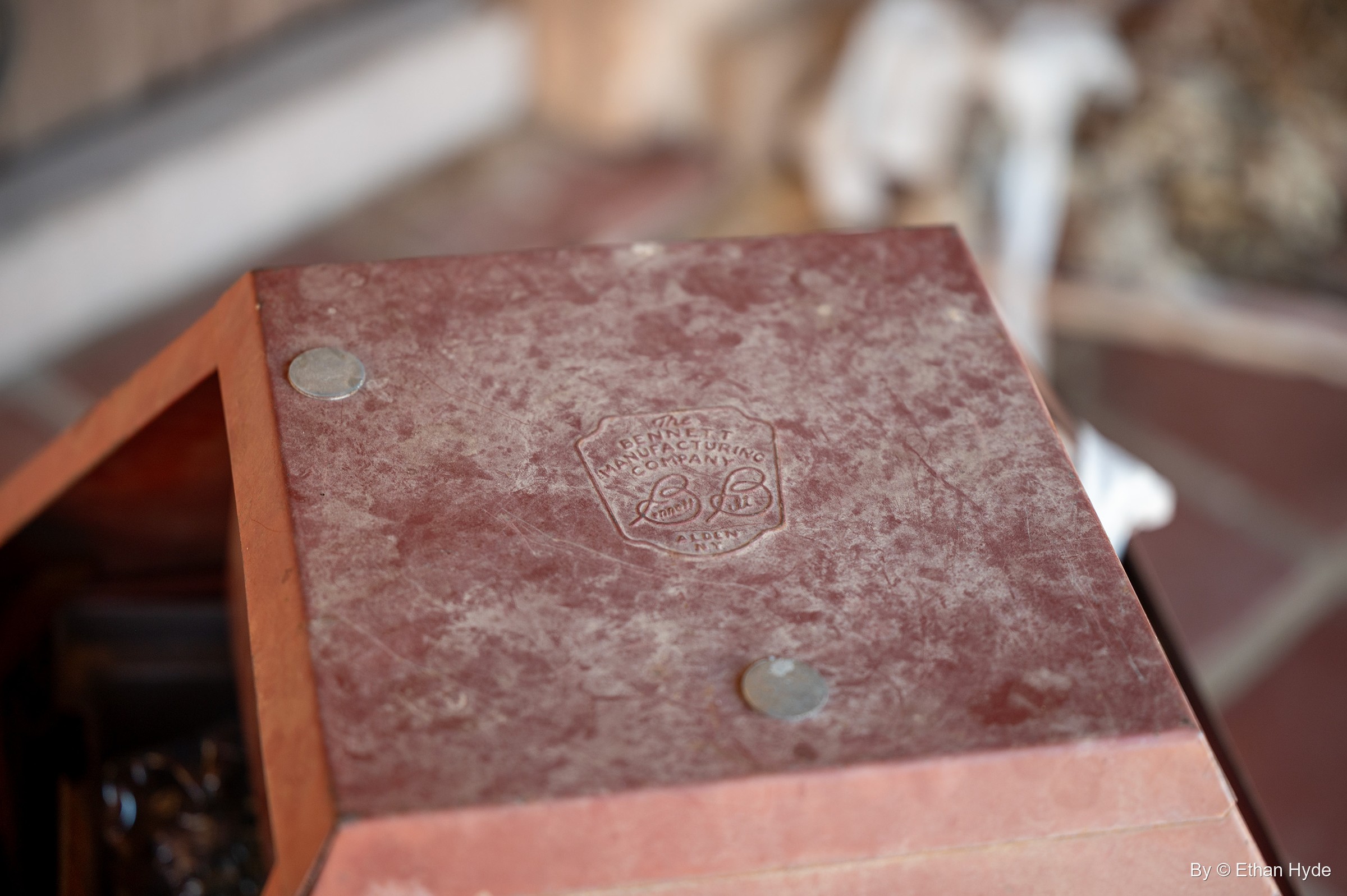 A stamped maker's mark reading "The Bennett Manufacturing Company, Alden, N.Y." on a red mottled surface at Scotty's Castle.