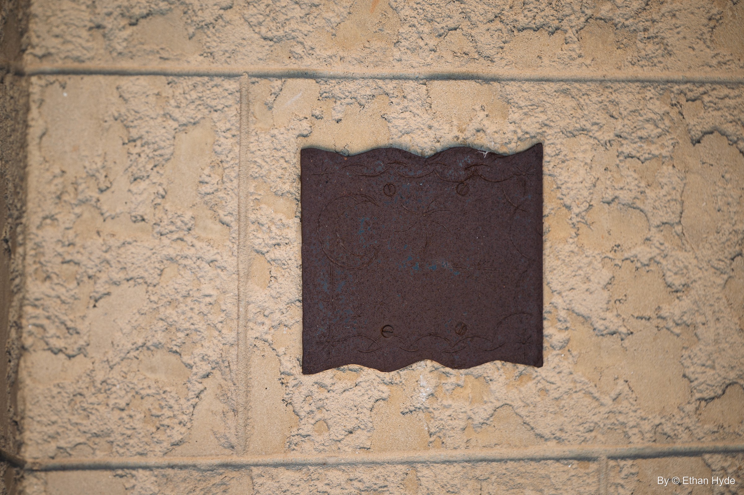A dark wavy-edged plate set into textured stucco at Scotty's Castle.