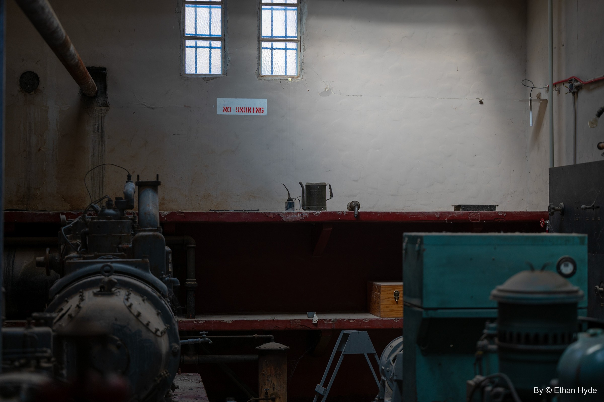 Inside the Powerhouse at Scotty's Castle, dark generating machinery lit by light from high windows on a pale wall.