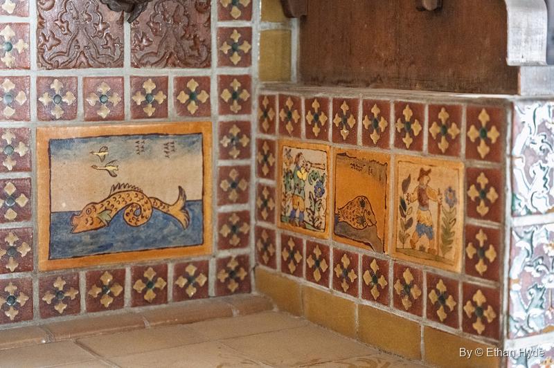A large hand-painted fish tile panel and figure tiles set among red and gold patterned tile in a corner of the kitchen at Scotty's Castle.