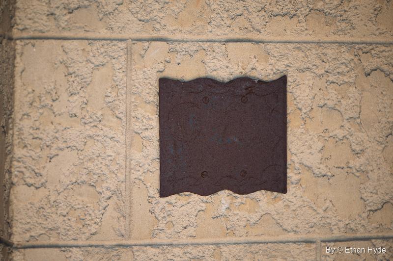 A dark wavy-edged plate set into textured stucco at Scotty's Castle.
