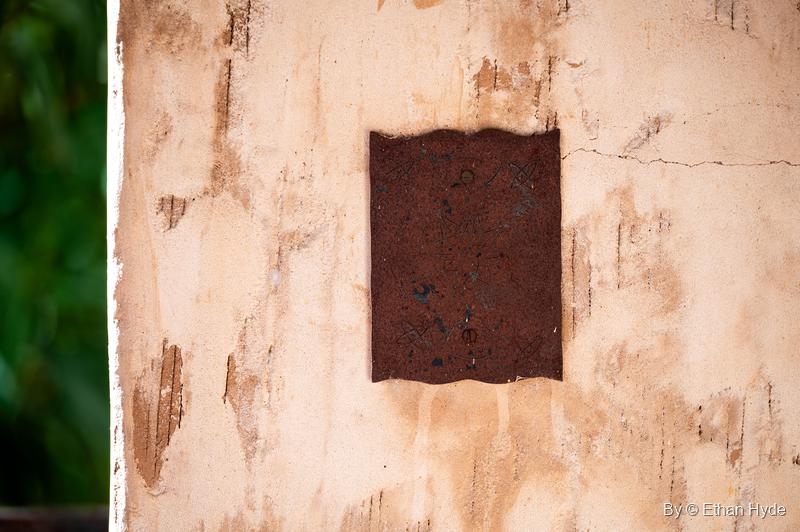 A rusted wavy-edged metal plate on a stained stucco wall at Scotty's Castle.