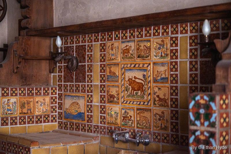 The tiled sink wall of the kitchen at Scotty's Castle, with the Ferdinand the Bull panel at its centre, animal tiles around it and wall lamps either side.