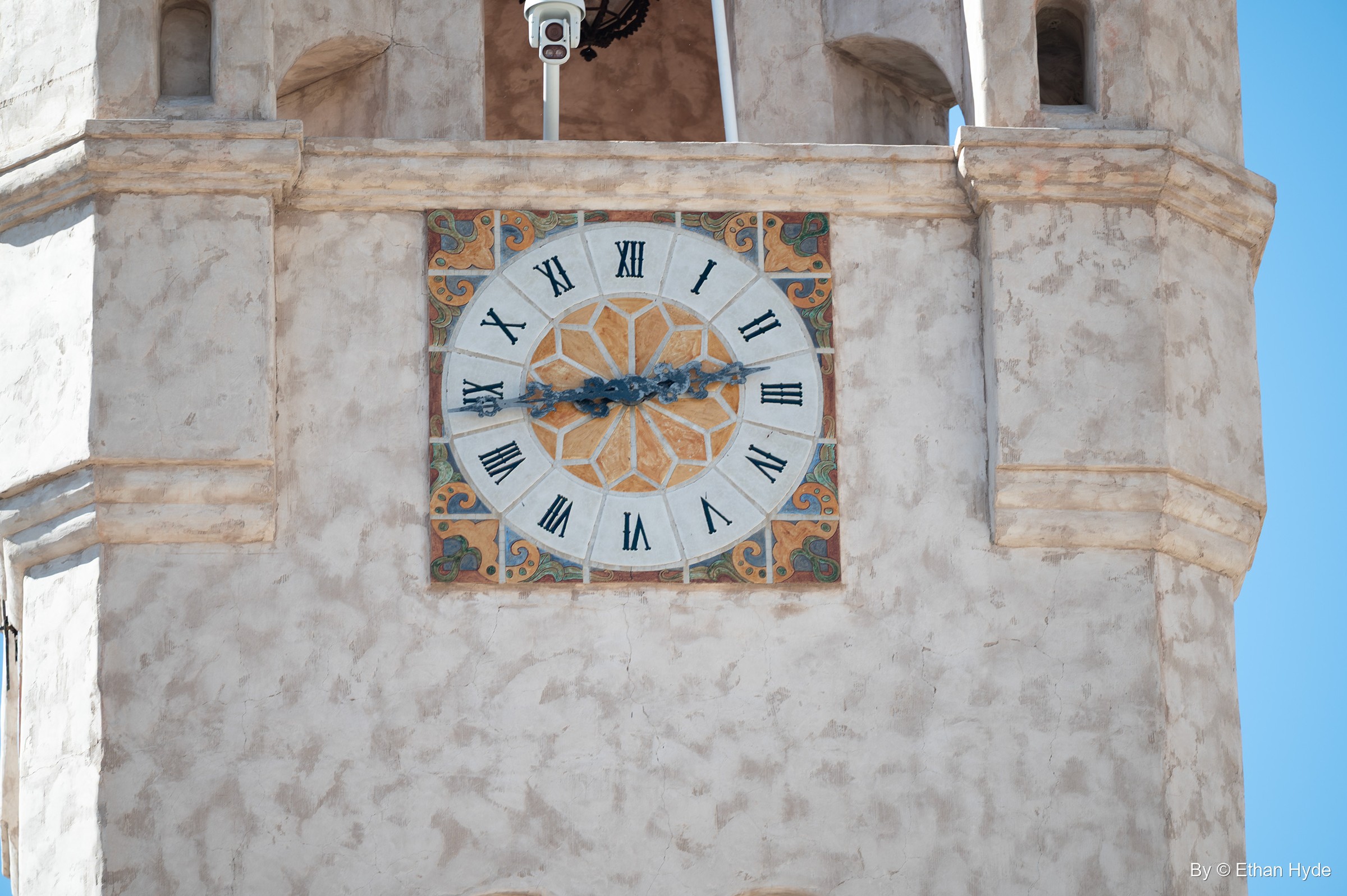 A Roman-numeral clock face set in patterned tile on the stucco wall of the Chimes Tower at Scotty's Castle.